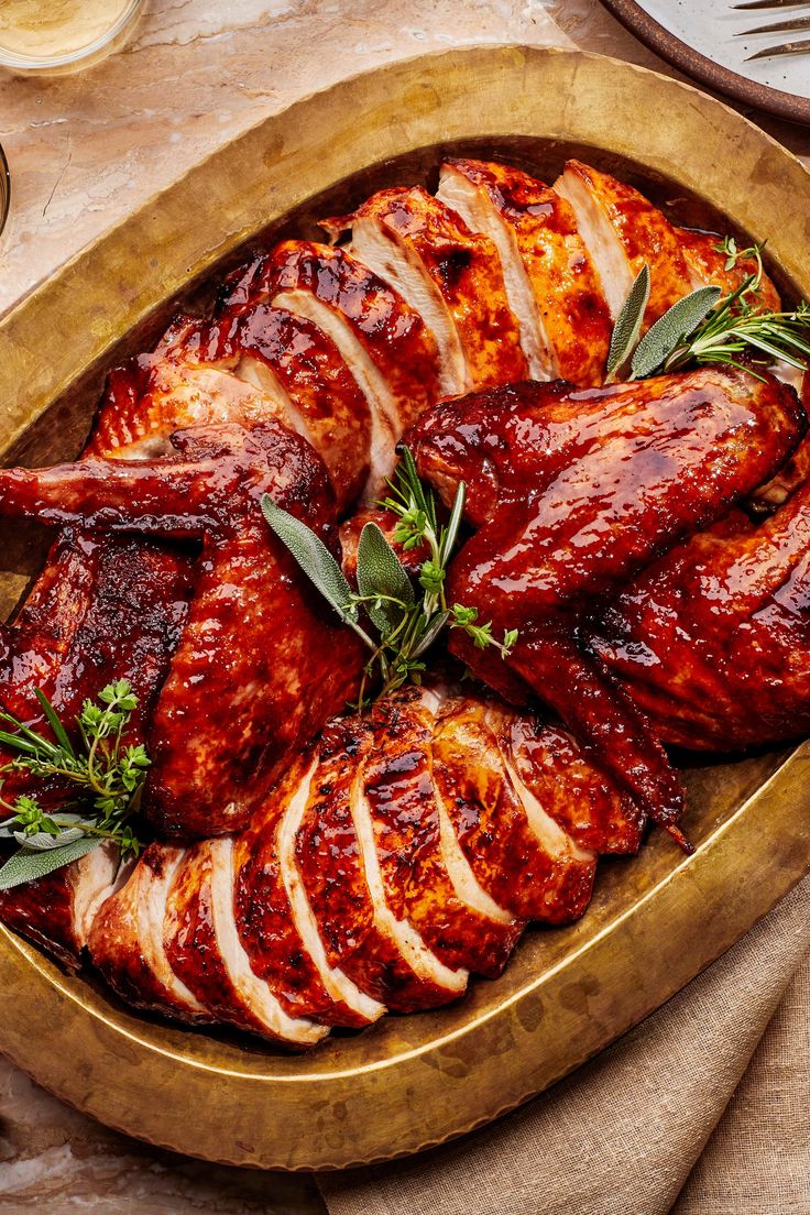 a roasting pan filled with meat and garnished with fresh herbs on the side