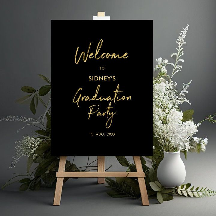 a black and gold graduation party sign next to some white flowers on an easel