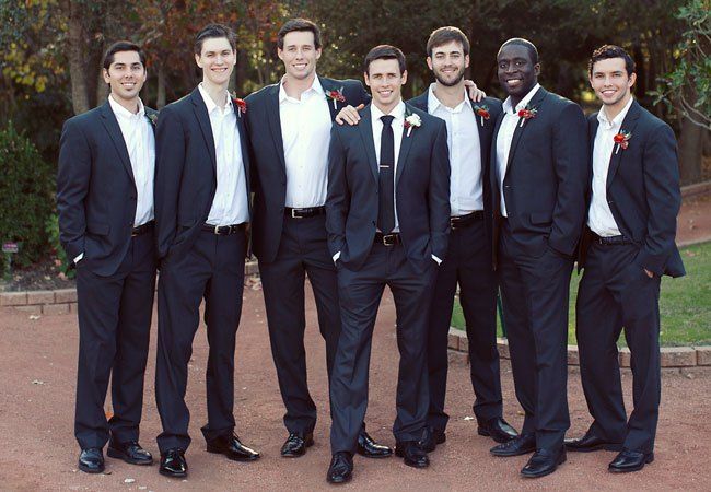 a group of young men standing next to each other in front of trees and bushes