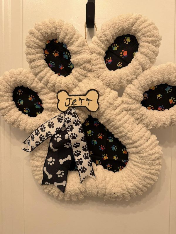 a dog paw door hanger is decorated with black and white paws, bones, and bones