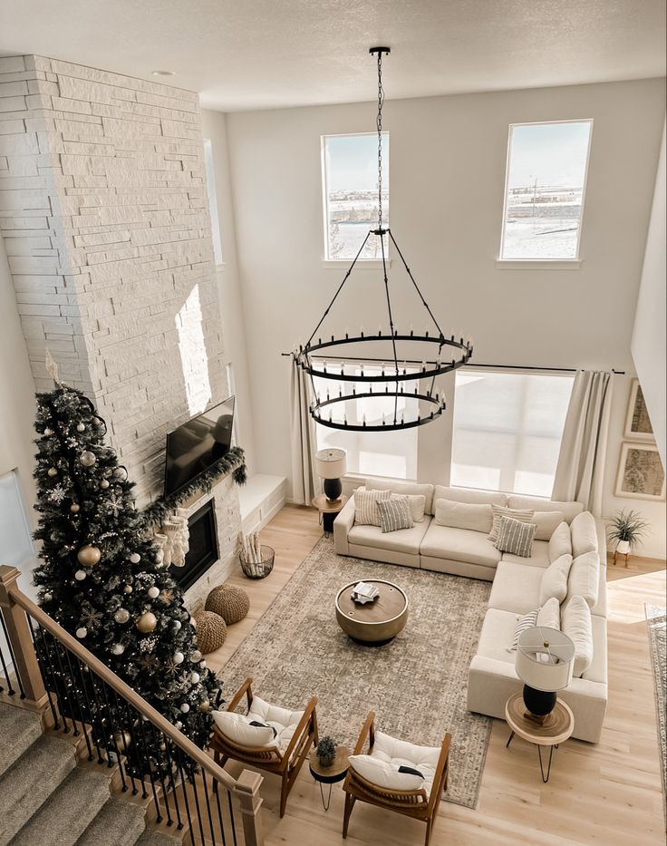 a living room filled with furniture and a christmas tree on top of a wooden floor