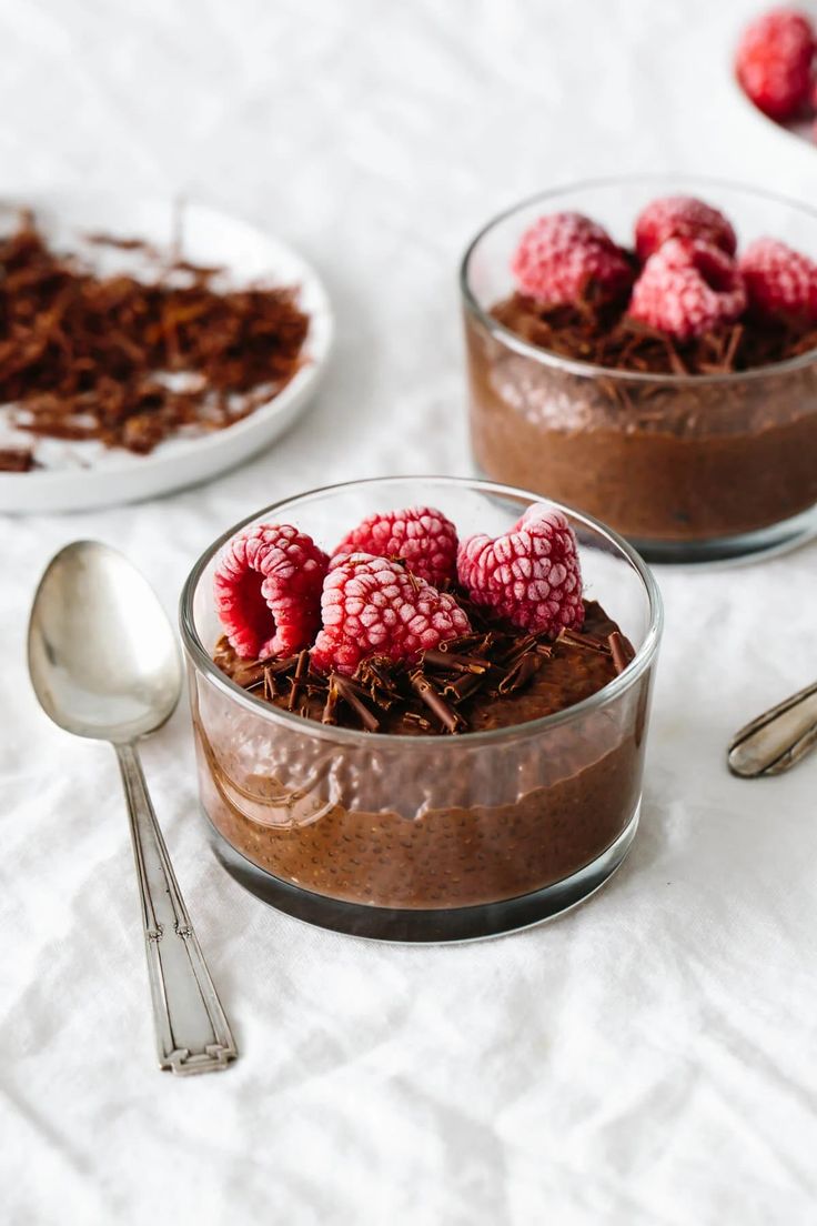 two small bowls filled with chocolate pudding and raspberries on top of each other