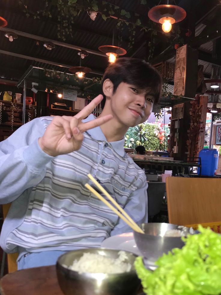 a man sitting at a table with chopsticks in his hand and bowl of food