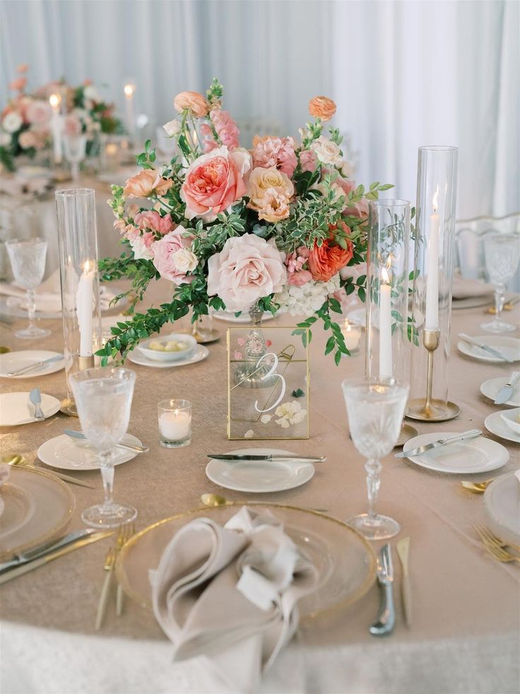 the table is set with plates, silverware and flowers