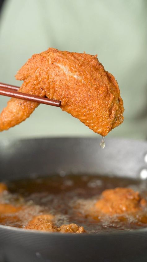 fried chicken being lifted from a pan with chopsticks