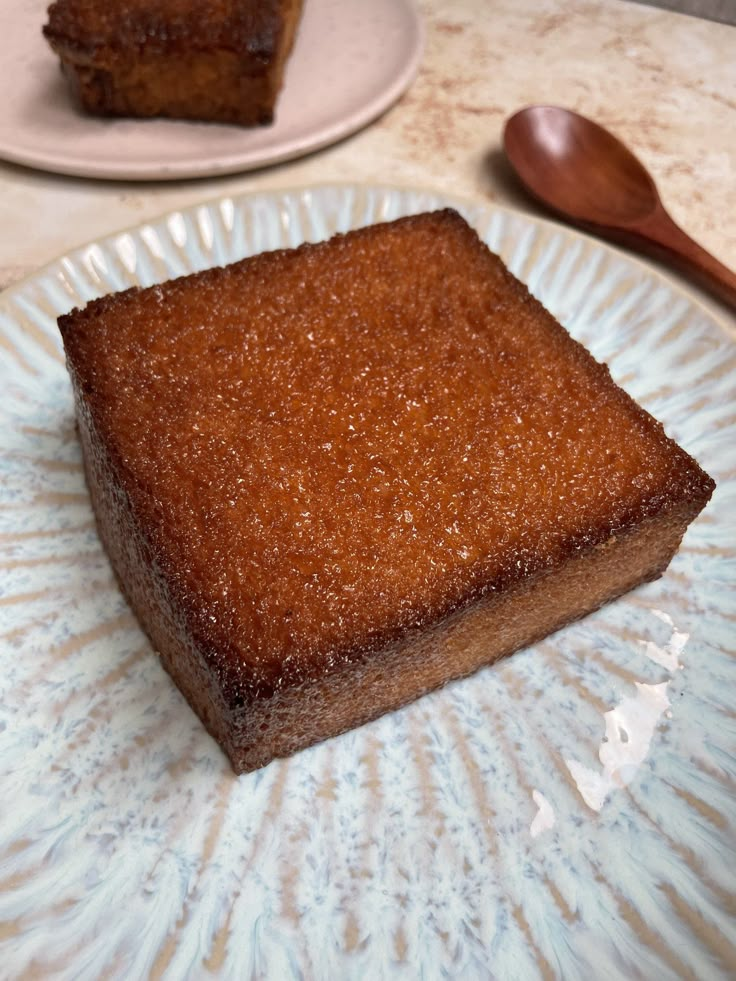 a piece of cake sitting on top of a white plate next to a wooden spoon