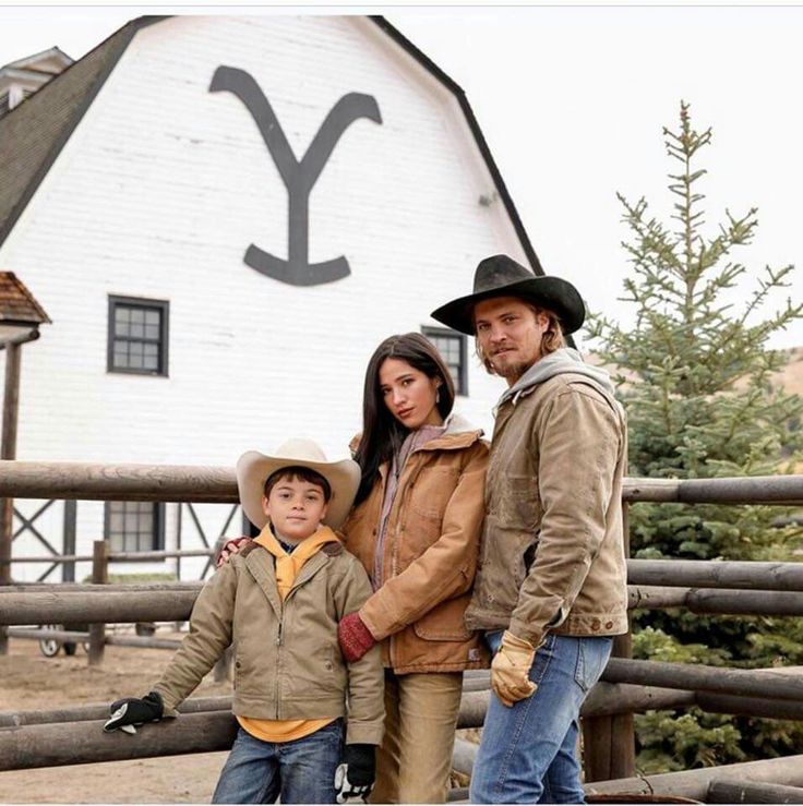 a man, woman and child standing in front of a barn with the letter y on it