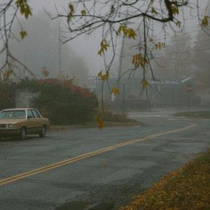 a car is driving down the road in the rain on a foggy day,