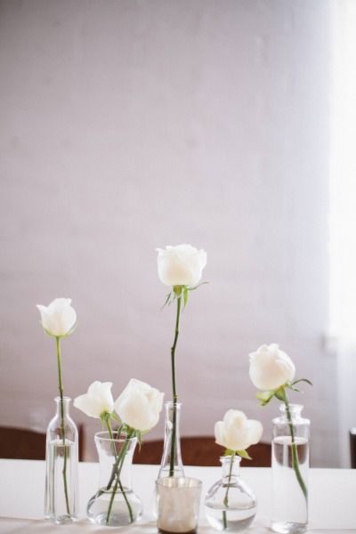 three vases filled with white flowers on top of a table