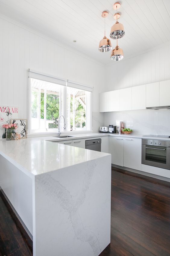 a white kitchen with an island in the middle and lots of counter space on one side