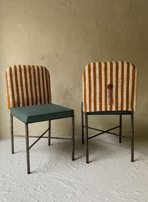 two chairs sitting next to each other in front of a white wall with stripes on them