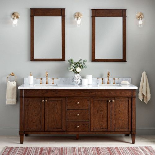 a bathroom with two sinks and mirrors on the wall next to a rug in front of it