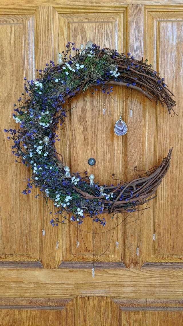 a wreath is hanging on the front door with blue and white flowers around it,