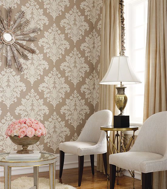 a living room with two chairs and a table in front of a wallpapered wall