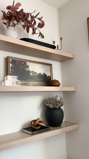 some shelves with vases and other items on them in a room that has white walls