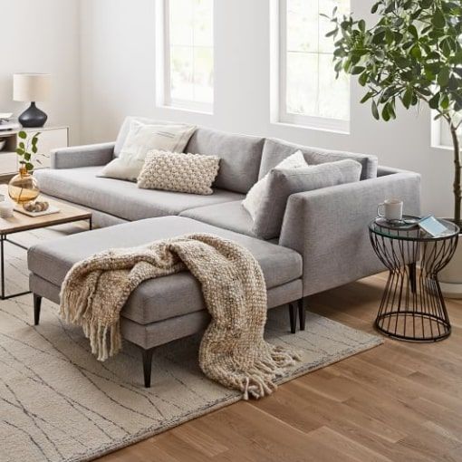 a living room with a couch, coffee table and plant in the corner on top of it