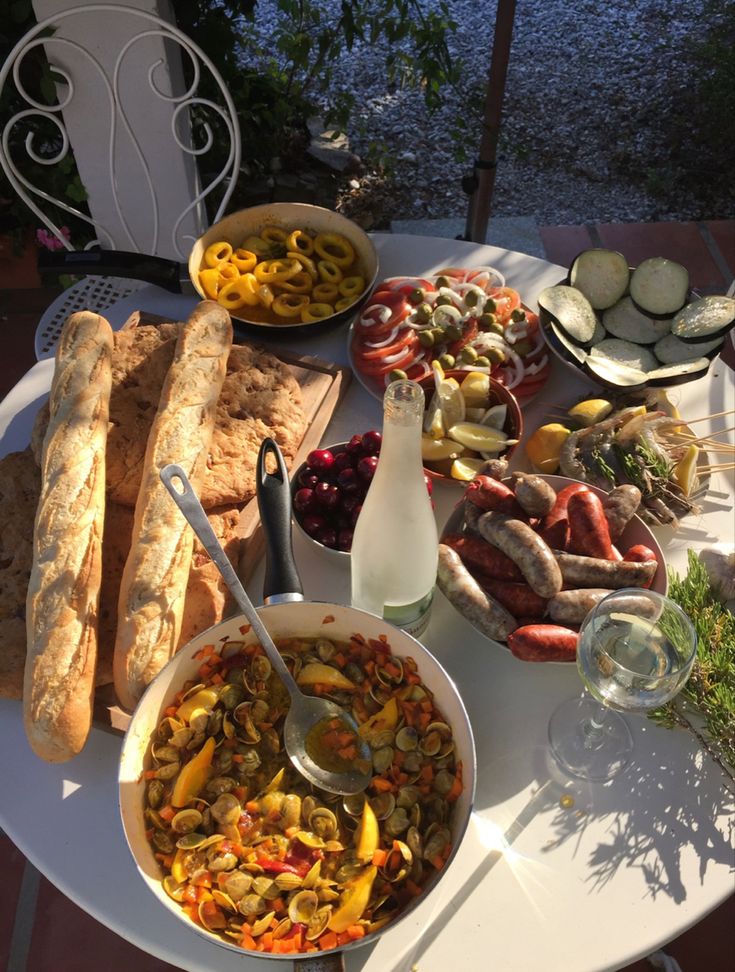 a table full of food including breads, sausages and other foods on it