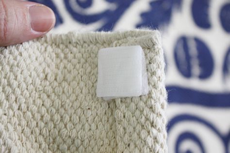 a hand holding a piece of white fabric with a square patch on the end of it