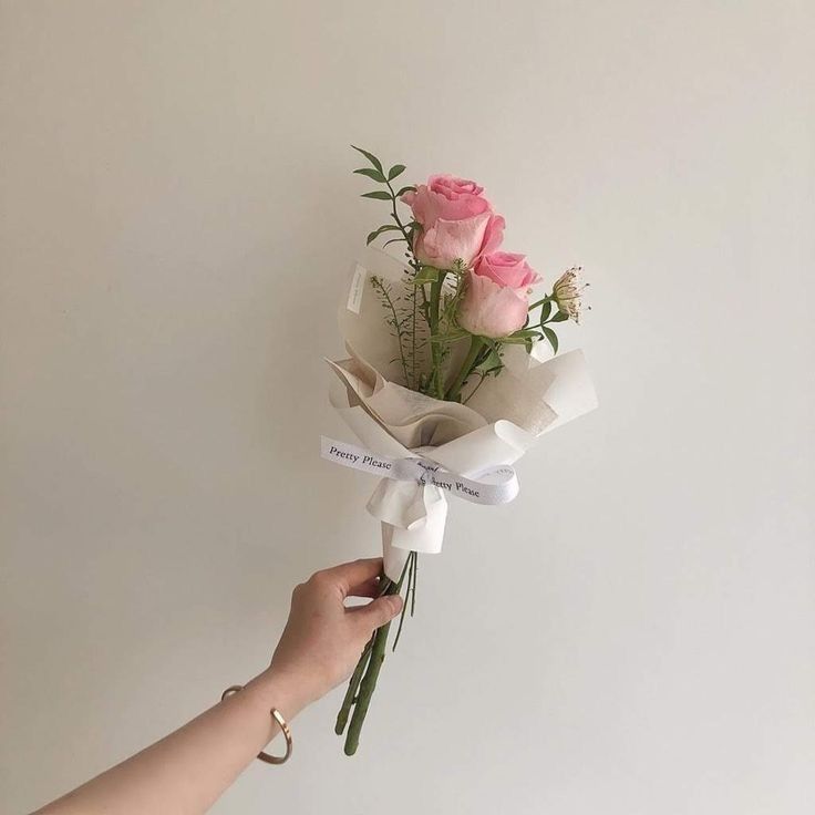 a hand holding a bouquet of pink roses