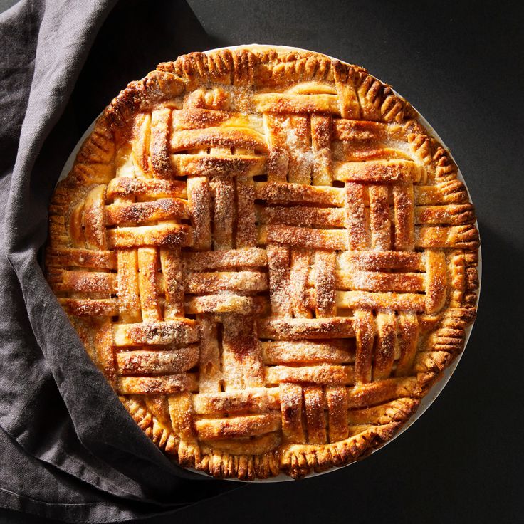 an overhead view of a pie on a table with a gray napkin and black background