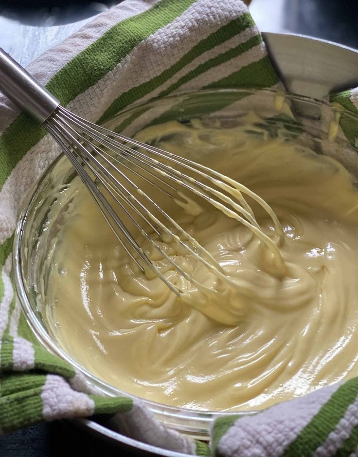 a bowl filled with batter and whisks on top of a green and white towel