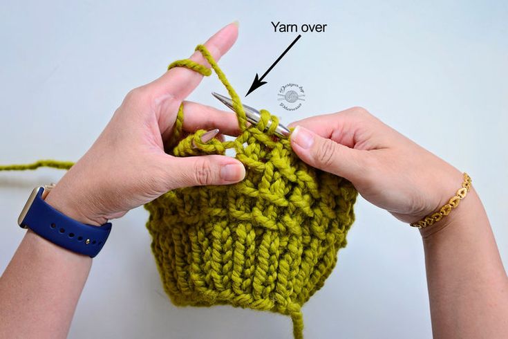 someone crocheting the stitchs on a green knitted object with two hands