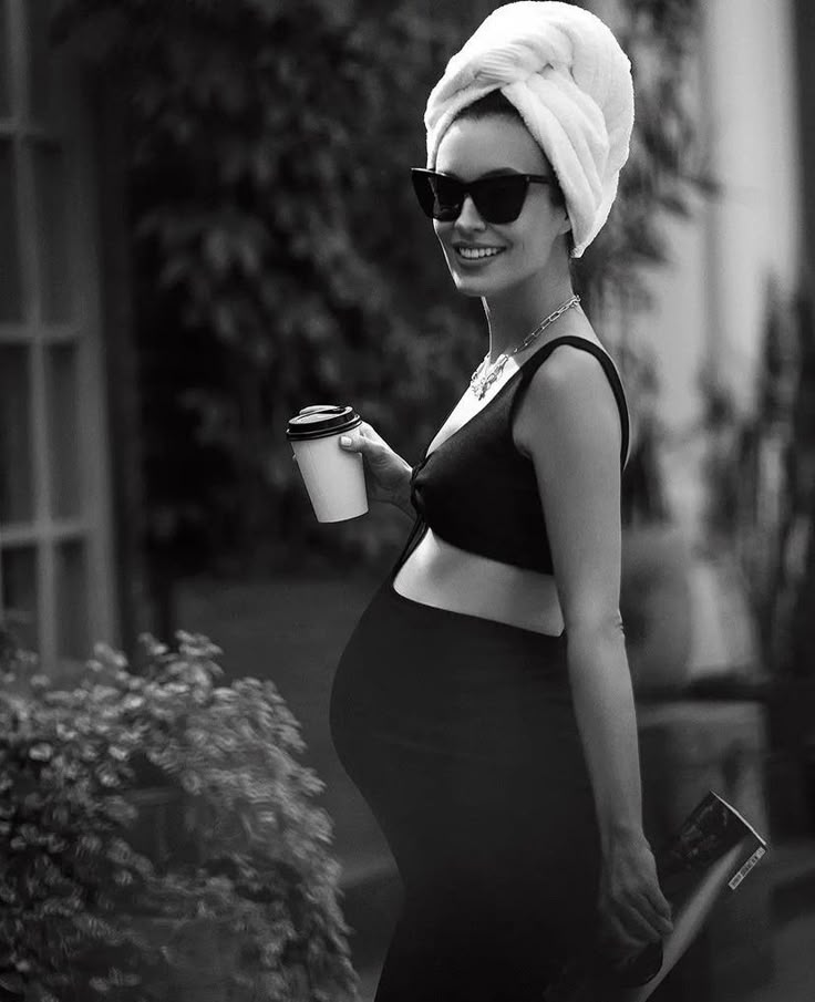 a woman with a towel on her head is holding a coffee cup and wearing sunglasses