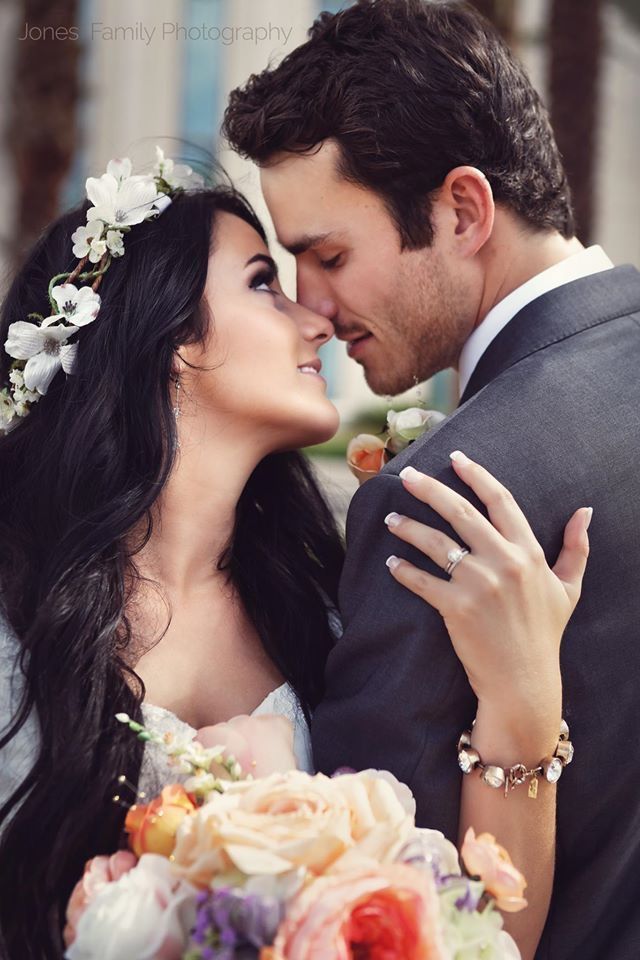 a bride and groom embracing each other with flowers in their hair