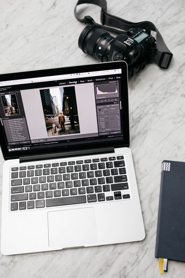 an open laptop computer sitting on top of a white marble table next to a camera