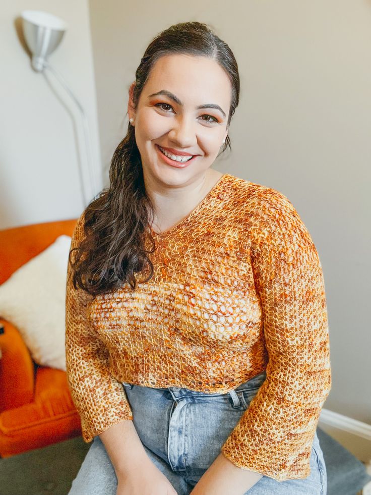 a woman sitting on top of a couch next to an orange chair and smiling at the camera