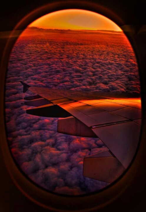 the view from an airplane window looking out at clouds and sunsets in the sky