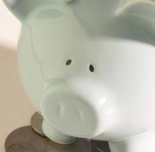 a white piggy bank sitting on top of a pile of coins with one eye open