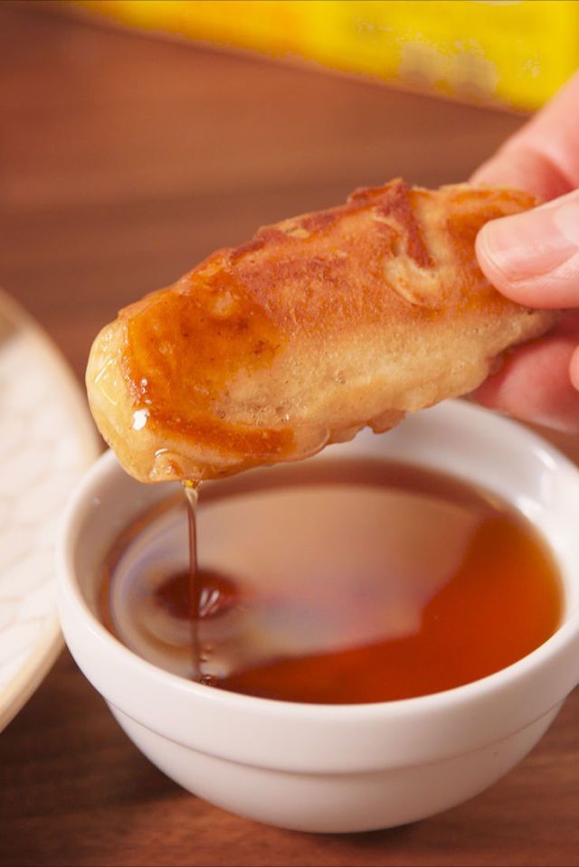 a person dipping some food into a bowl