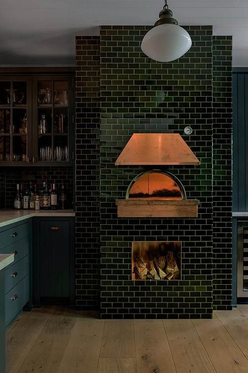 a large brick oven in the middle of a kitchen with blue cabinets and wood floors