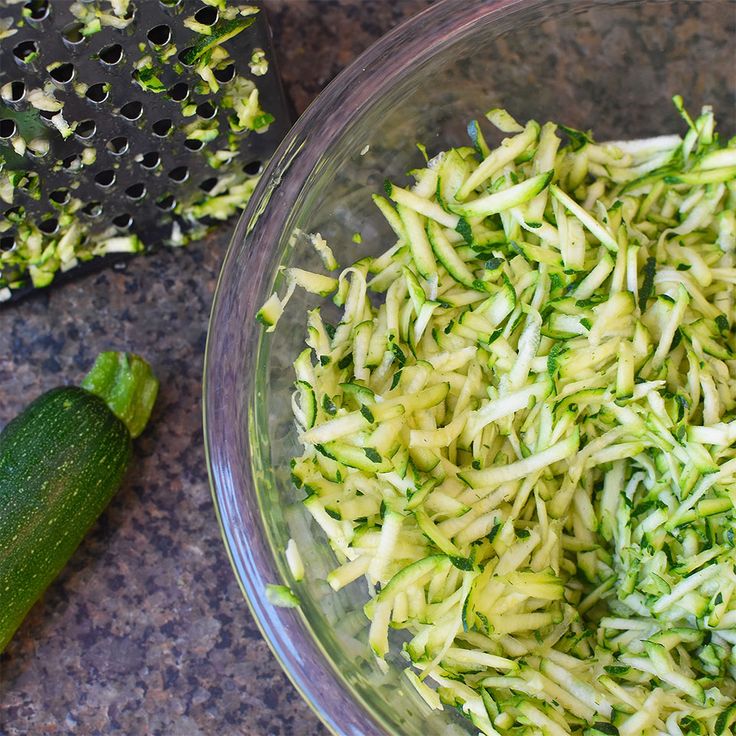 zucchini sprouts in a glass bowl next to a cucumber