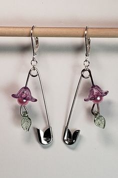 two pink flowers are hanging from silver hooks