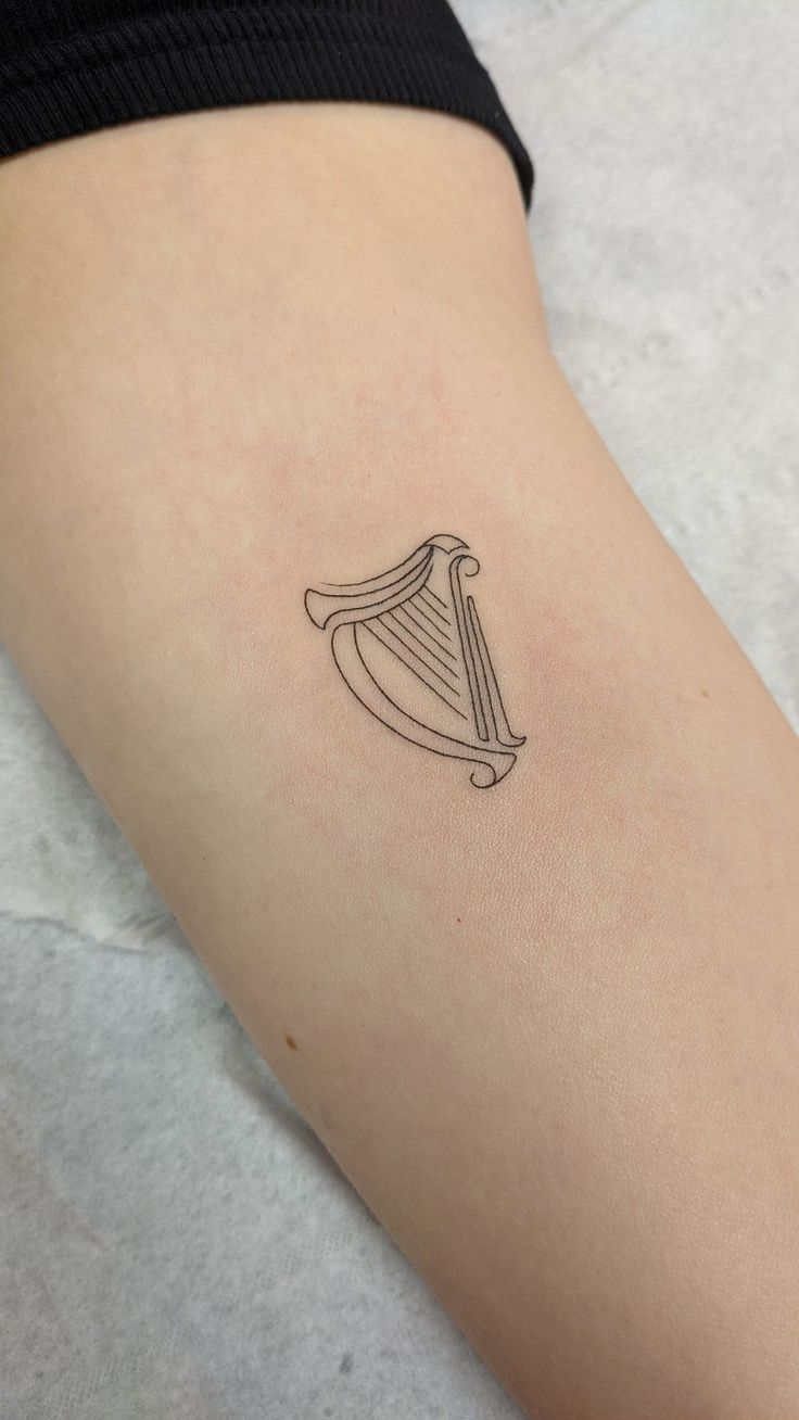 Harp tattoo Simple Harp Tattoo, Ireland Harp Tattoo, Harp Tattoo Minimalist, Unique Irish Tattoos, Irish Dance Tattoo, Irish Symbols Tattoos, Small Ireland Tattoo, Irish Harp Tattoos For Women, Guinness Harp Tattoo