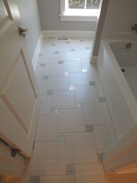 an empty bathroom with tiled floors and white walls, looking down at the shower stall