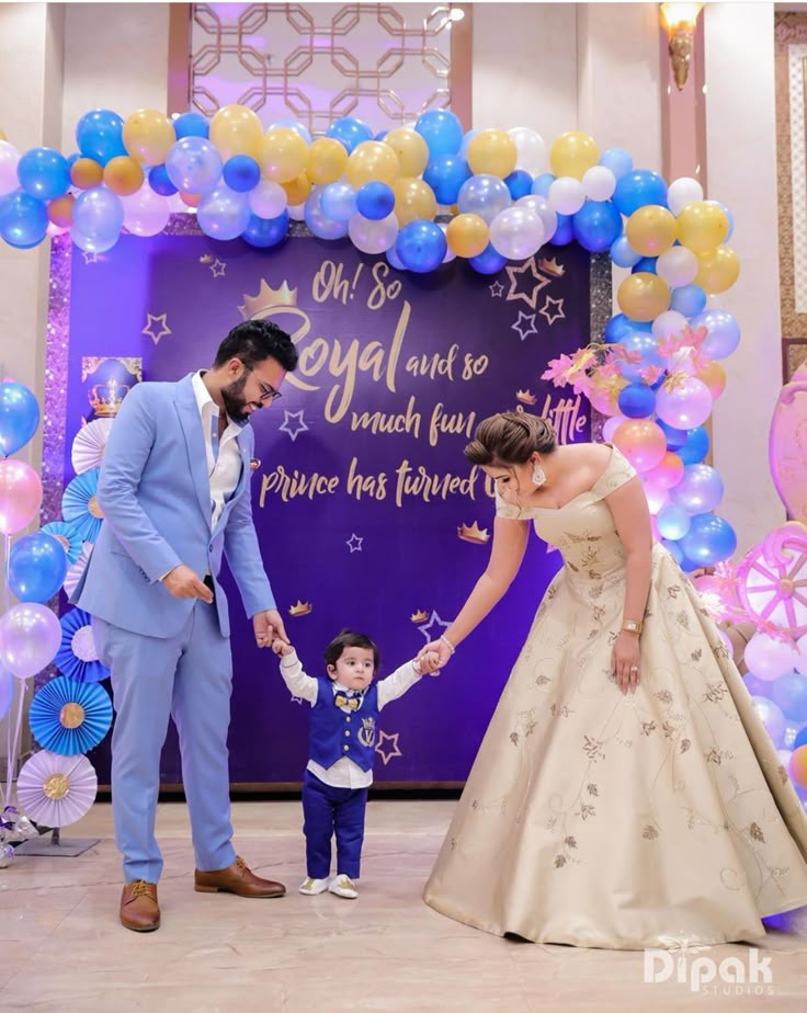 a man and woman holding hands in front of a baby's first birthday backdrop