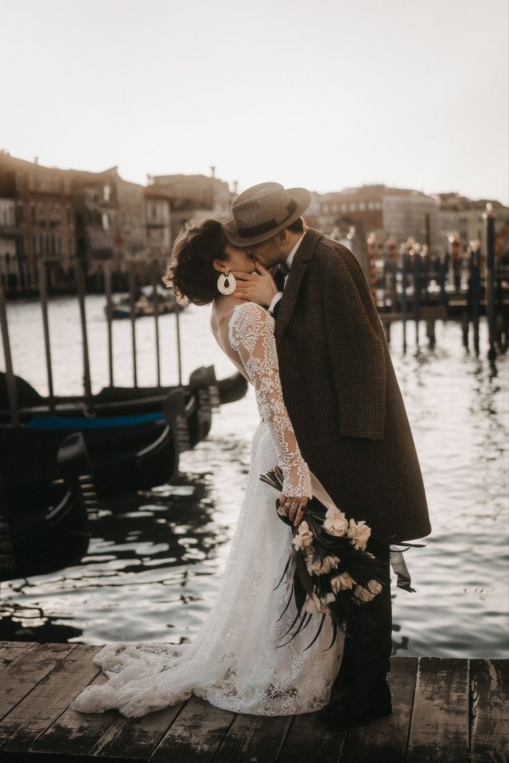 a bride and groom kissing on a dock in venice, italy by the water's edge