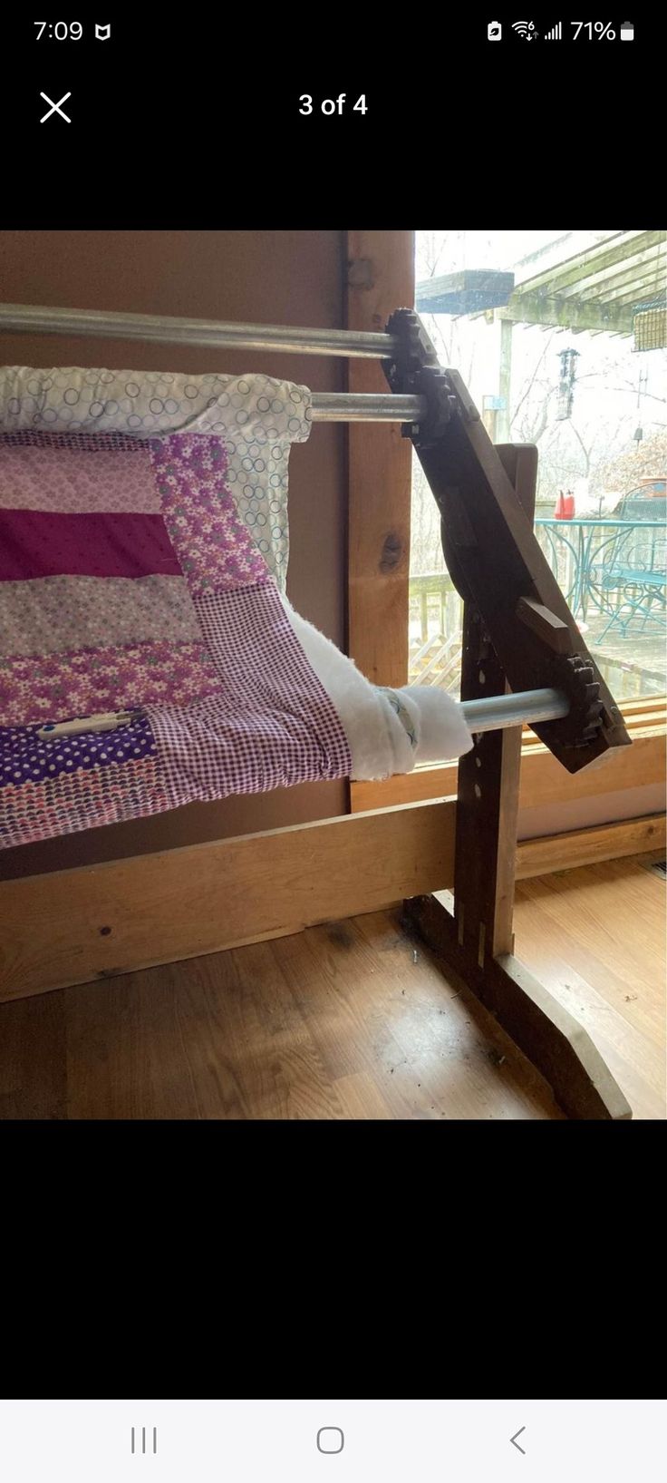 the bed frame is made from wood and has pink and white quilts on it