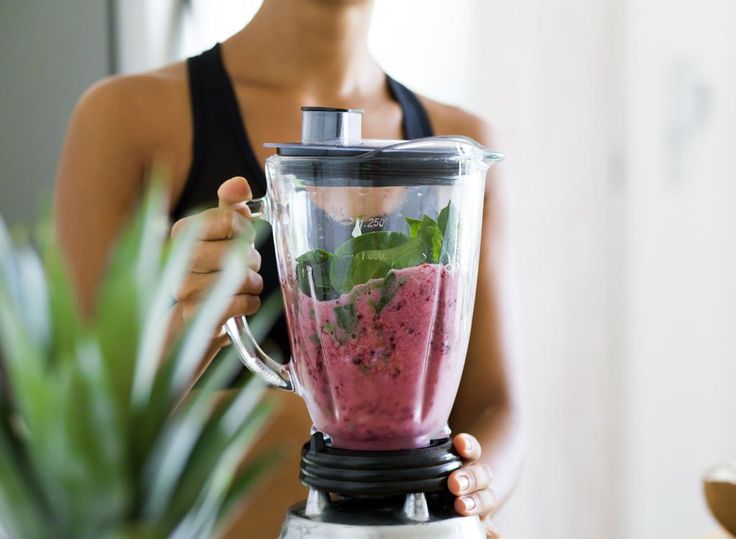 a woman holding a blender filled with pink liquid