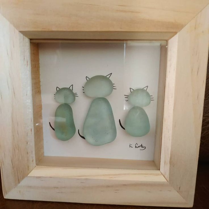 three glass cats in a wooden frame