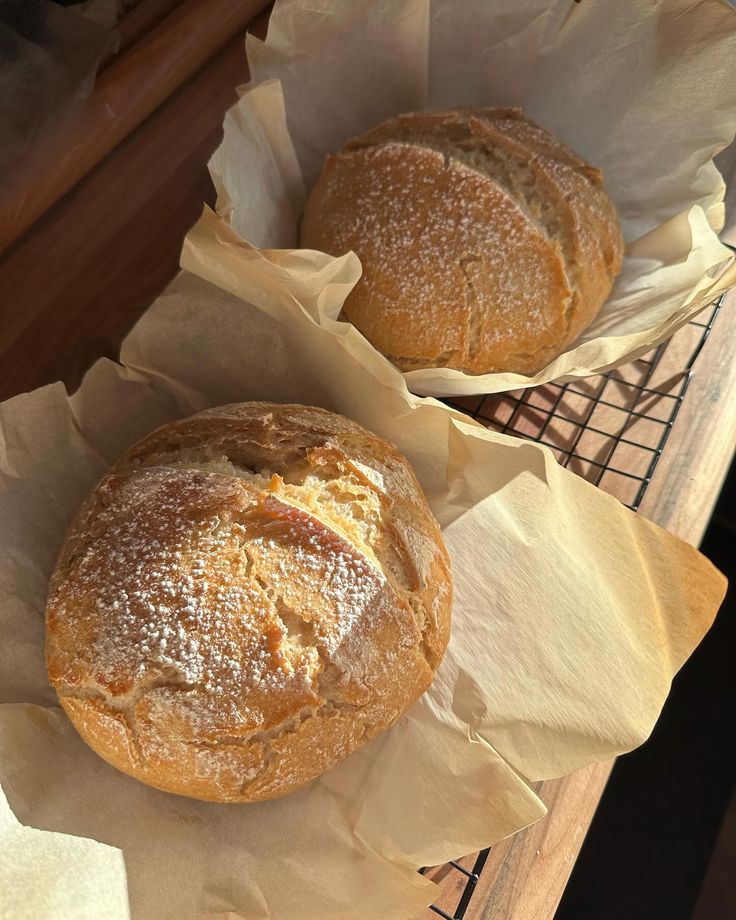 two loaves of bread sitting on top of paper wrapped in wax paper next to each other