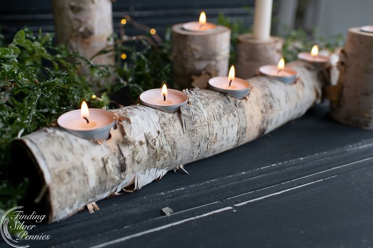 several lit candles sitting on top of a wooden log