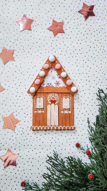 a gingerbread house is hanging on the wall next to some christmas trees and stars