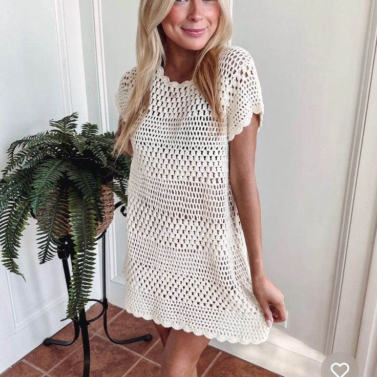 a woman standing next to a potted plant wearing a white crochet dress