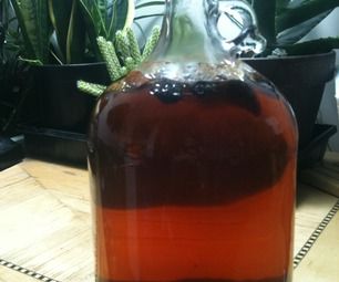 a glass bottle filled with liquid sitting on top of a table next to potted plants