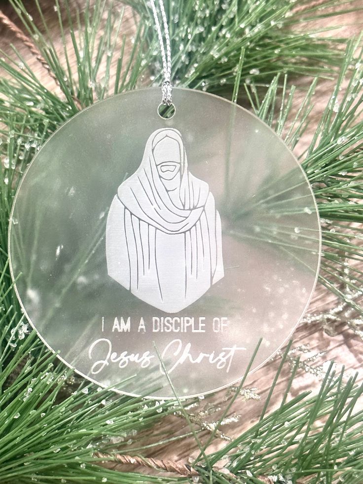 a glass ornament hanging from a tree with the words, i am a dispple of jesus christ