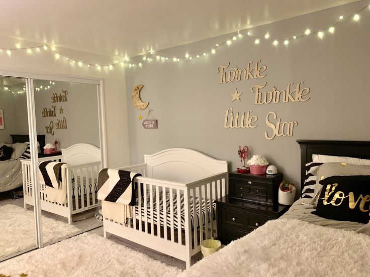 a baby's room with two white cribs and lights on the wall